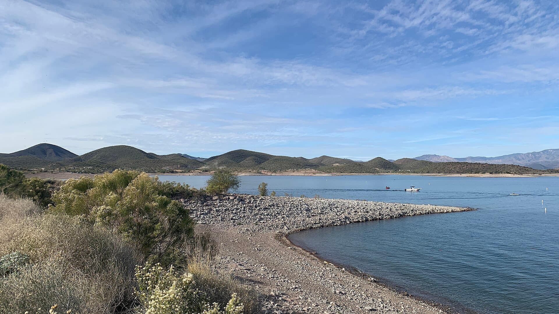 Blue water of Lake Pleasant in Peoria, Arizona with a rocky shoreline and desert hills under a soft sky.
